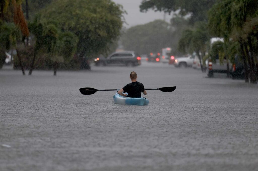 Man kayaking on the street in heavy rain - Future Proof by The Paulele Hale Organization